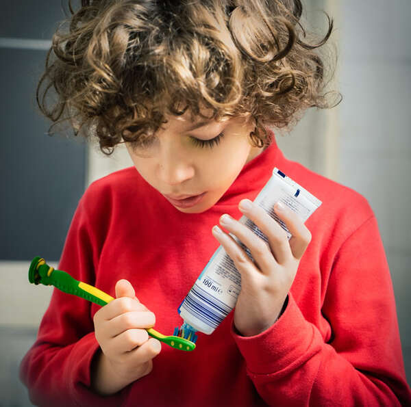 Child putting toothpaste on a brush